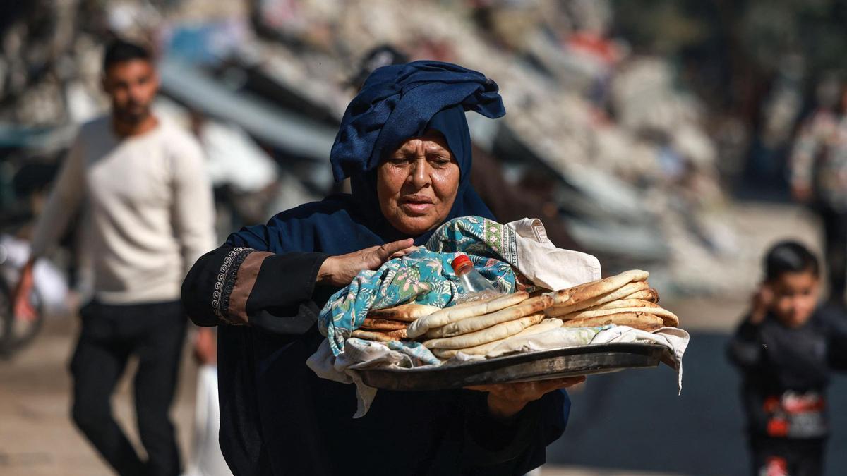 Una mujer transporta unas hogazas de pan en Gaza.