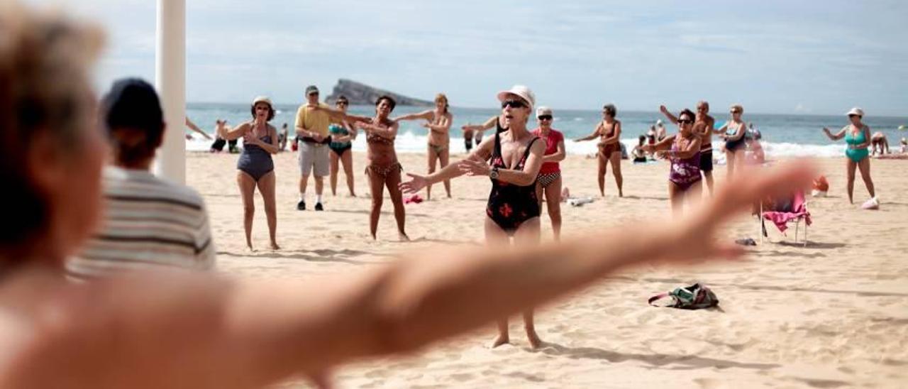 Turistas de la tercera edad haciendo gimnasia en la playa de Poniente de Benidorm en una imagen reciente.