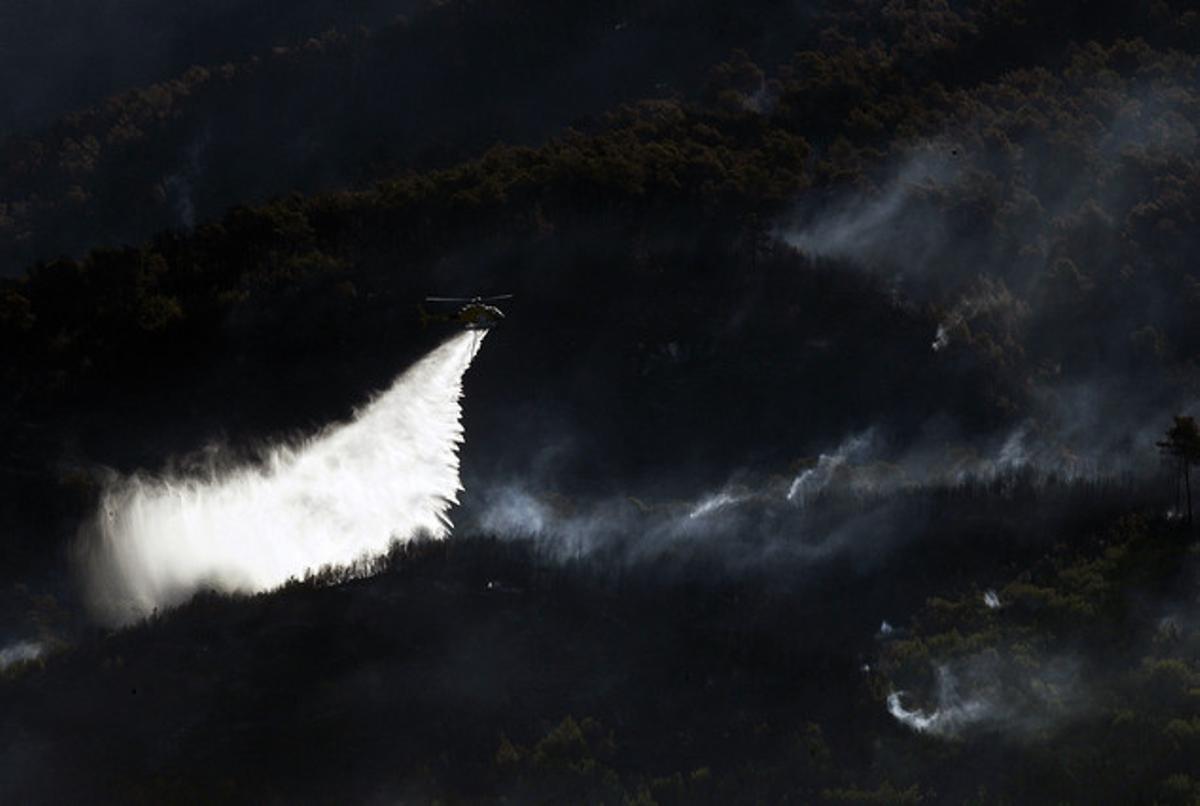 Un helicòpter llança aigua sobre el foc de Vallirana. Un helicòpter llança aigua sobre el foc de Vallirana.
