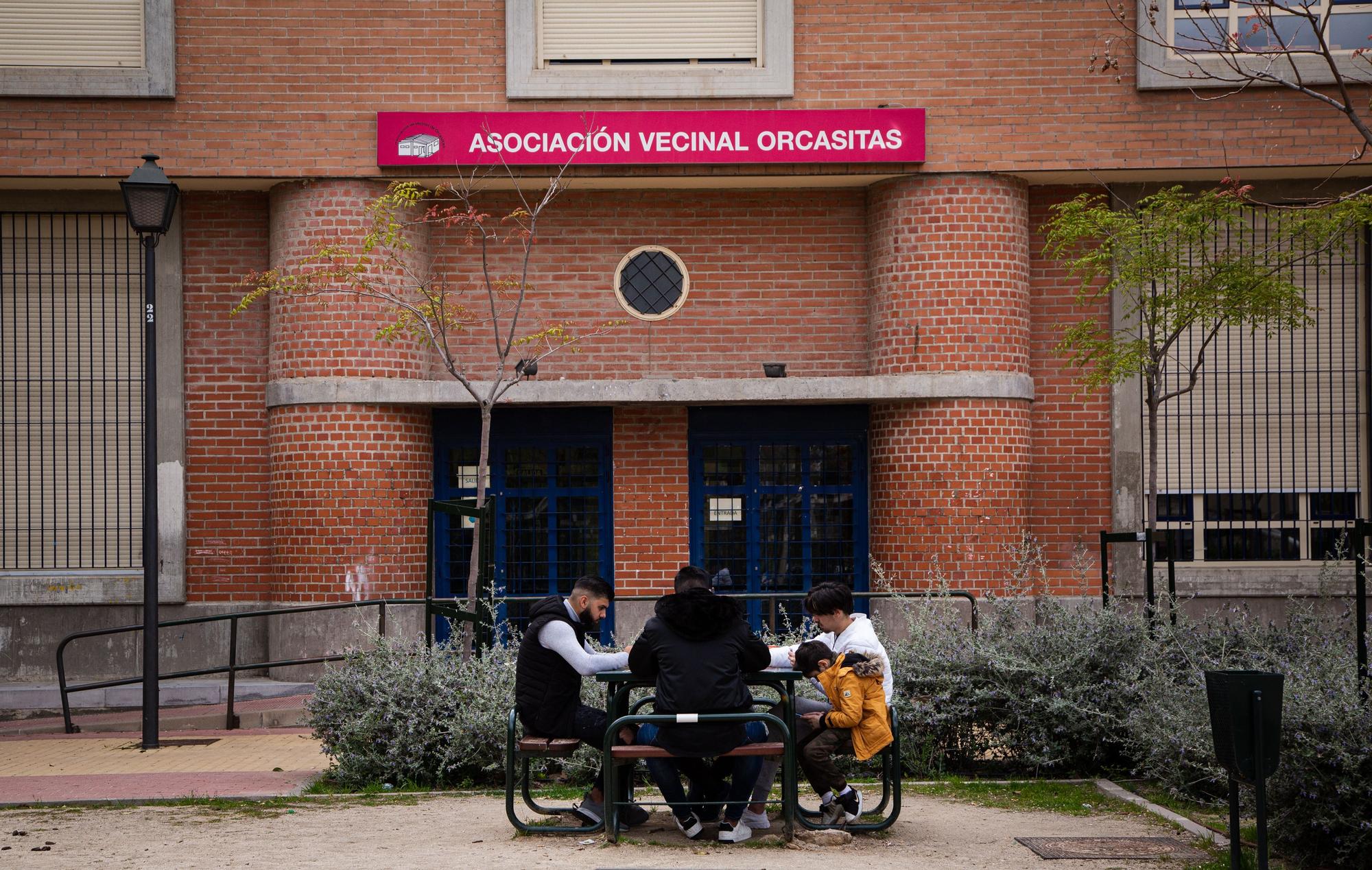 Cuatro personas juegan frente a la puerta de la Asociación de Vecinos de Orcasitas, en Madrid.