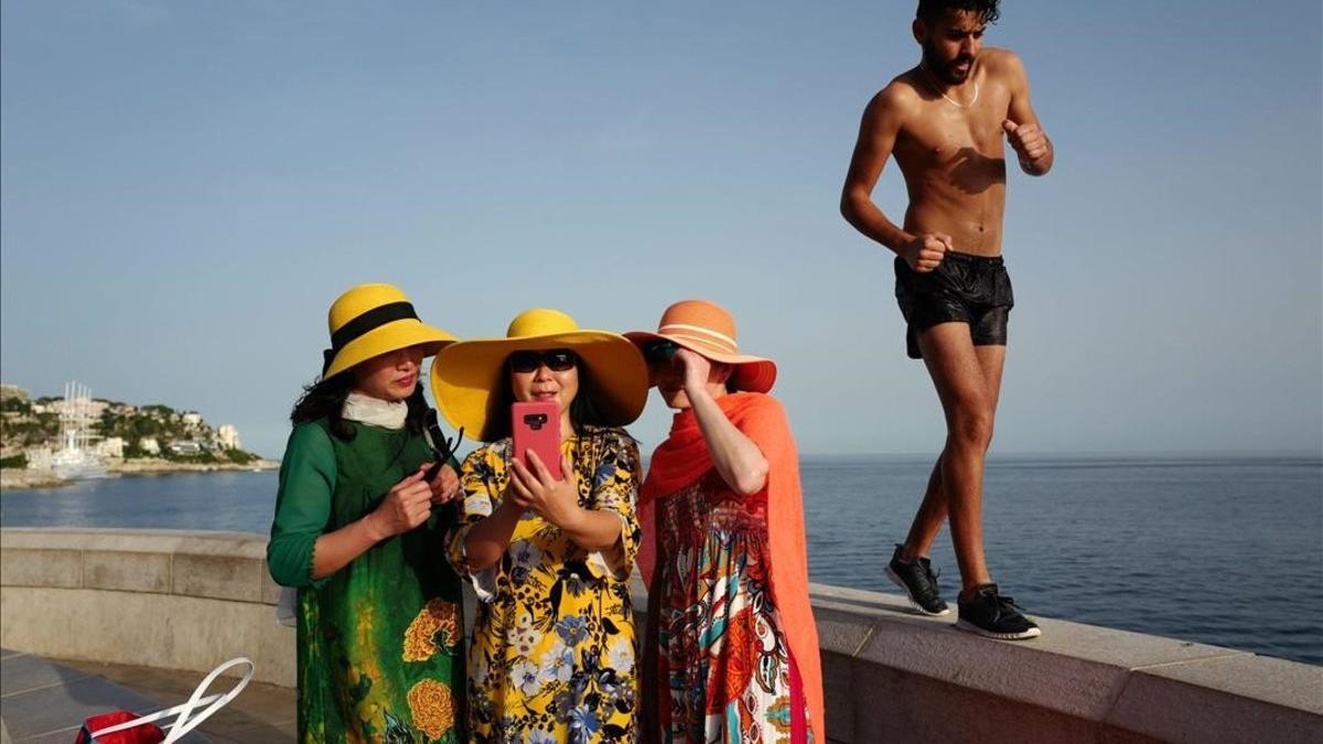 Un hombre pasa junto a unas turistas que se hacen una foto en Niza, Francia
