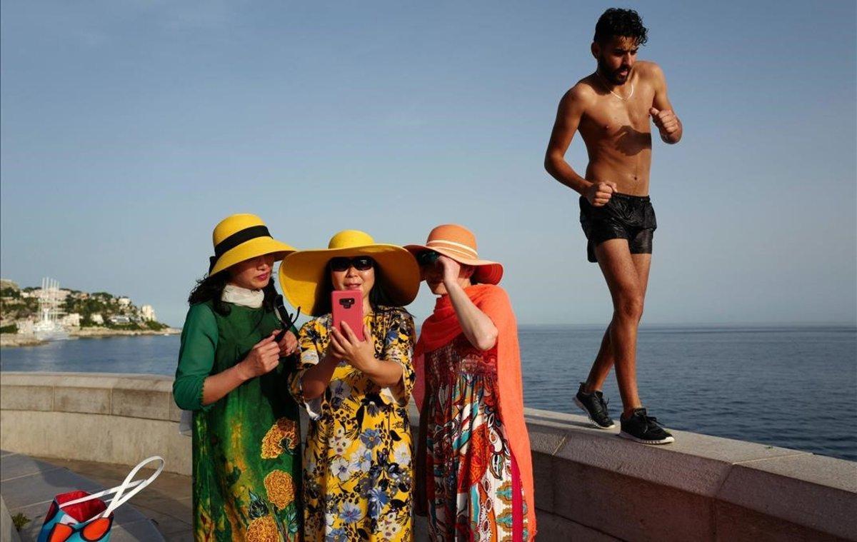 Un hombre pasa junto a unas turistas que se hacen una foto en Niza, Francia.