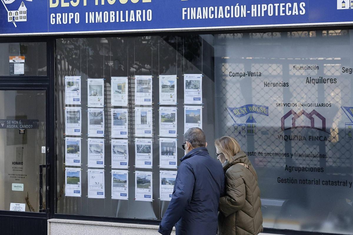 Una pareja pasa ante el escaparate de una agencia inmobiliaria en Santiago