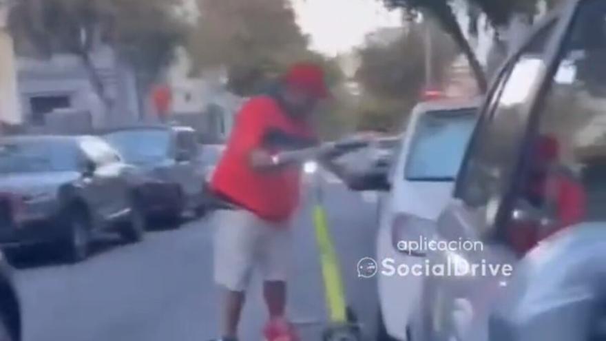 Un hombre rompe un espejo retrovisor subido en un patinete eléctrico