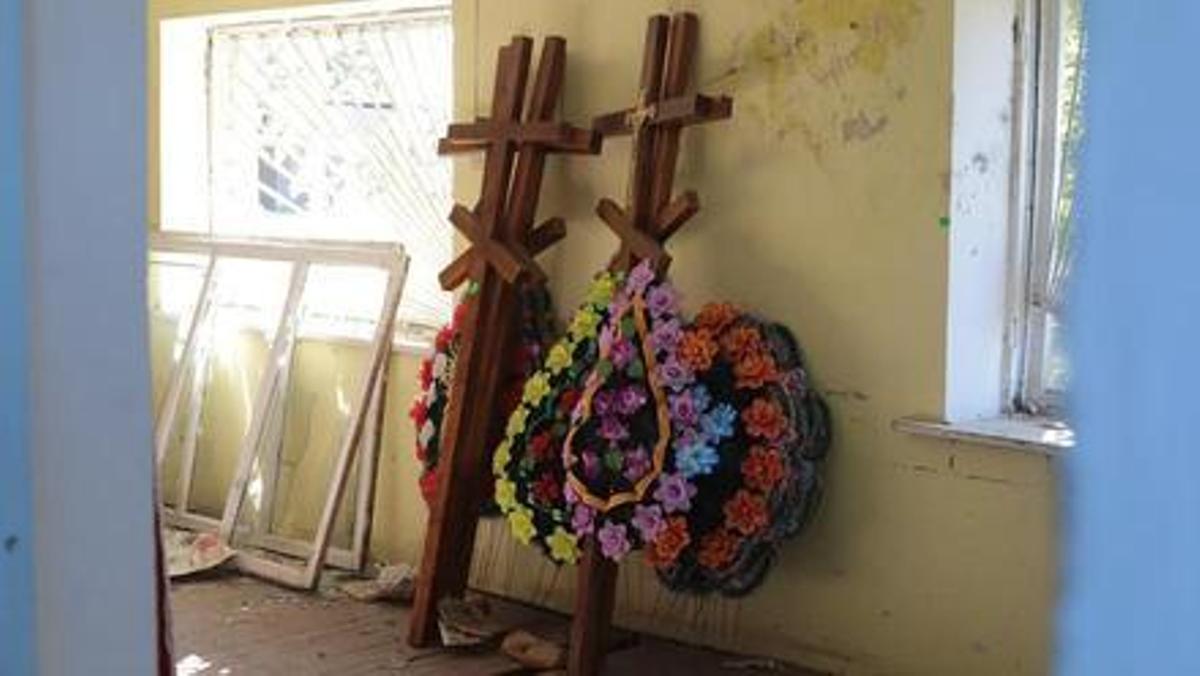 Cruces y coronas de flores esperan en un colegio a los próximos ucranianos caídos en el frente.