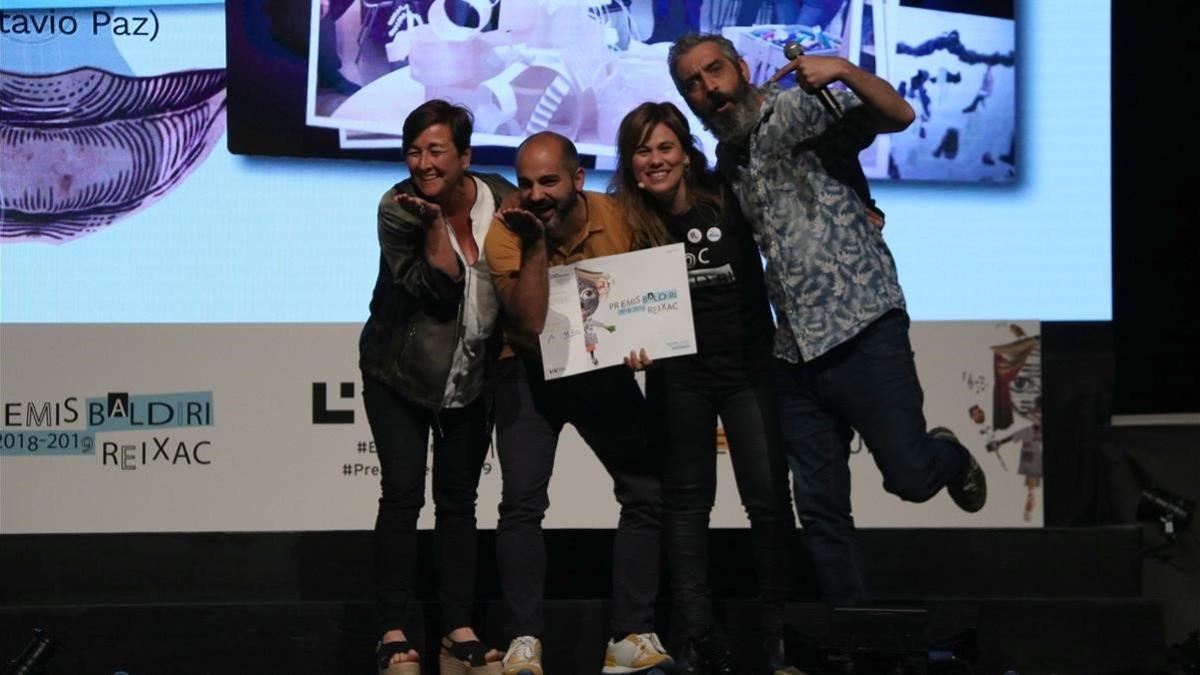 Elena Guillén y Xavi López, jefe de estudios y director de la escuela Octavio Paz, con el premio, junto a los presentadores Marta Esteve y Roger de Gràcia.