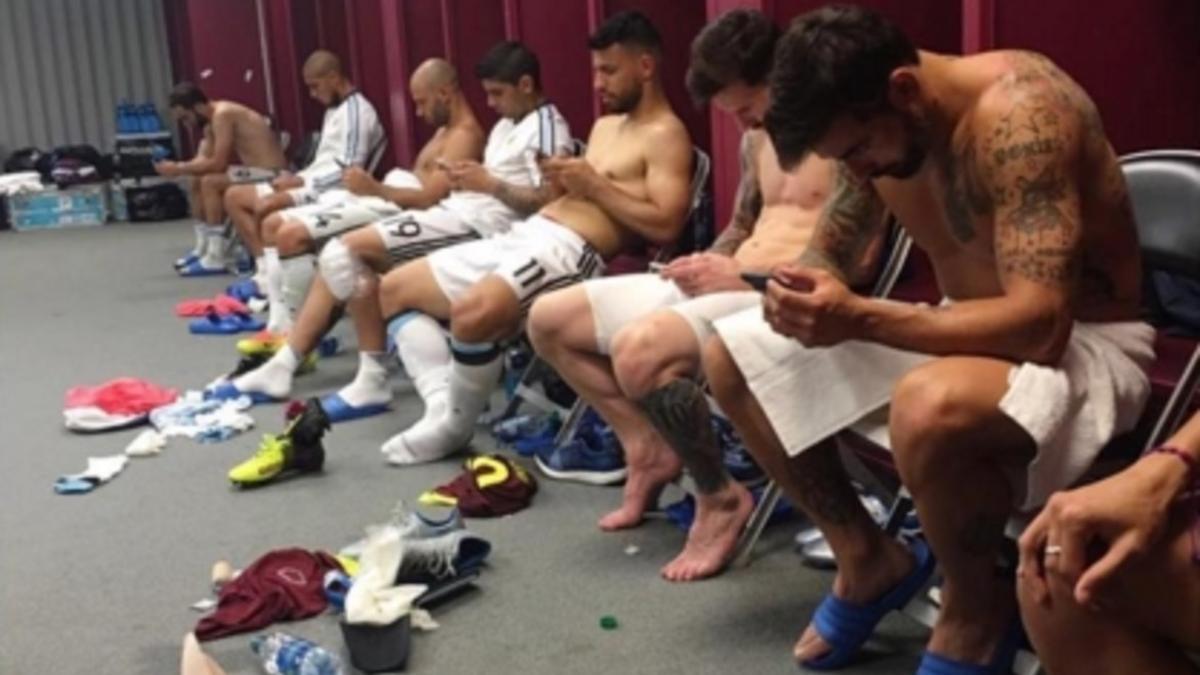 Los jugadores de Argentina, pendientes de sus teléfonos móviles tras la victoria sobre Venezuela.