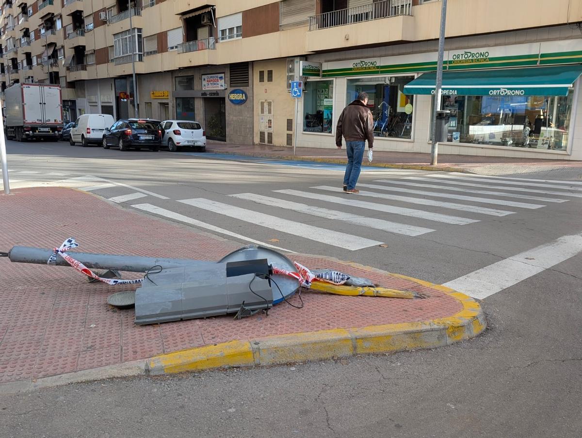 Uno hombre pasa por delante de unos de los semáforos que derribó un conductor en Xàtiva, en una imagen captada hoy.