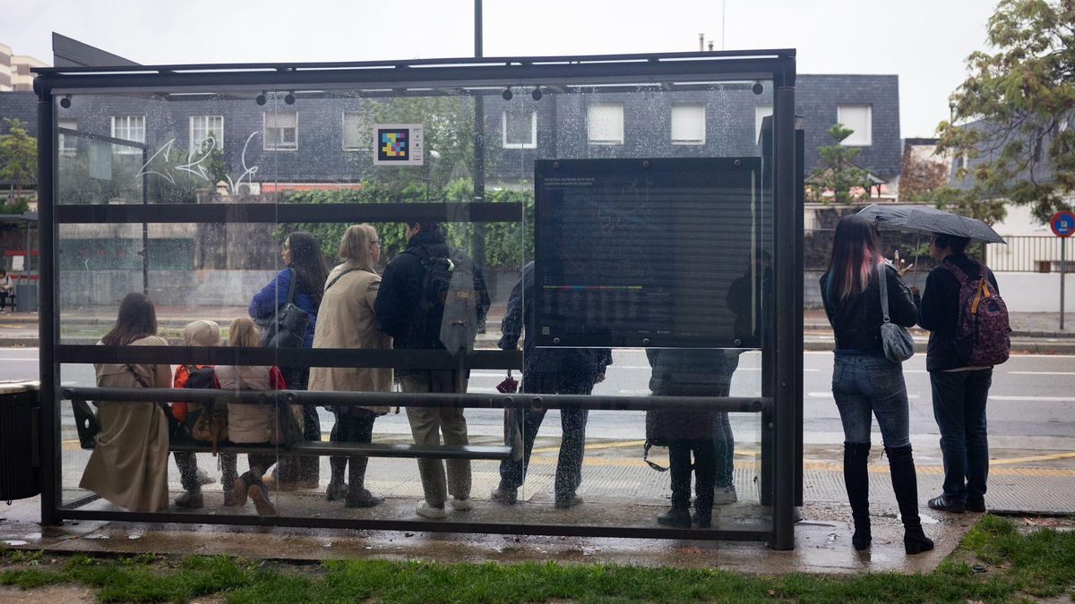 Varias personas esperan al autobús en una marquesina de Zaragoza capital este lunes durante la huelga convocada por los sindicatos