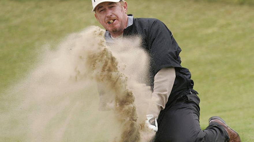 prácticas. Miguel Ángel Jiménez, en una postura acrobática, saca la bola del ´búnker´, ayer, en la previa del Abierto Británico.