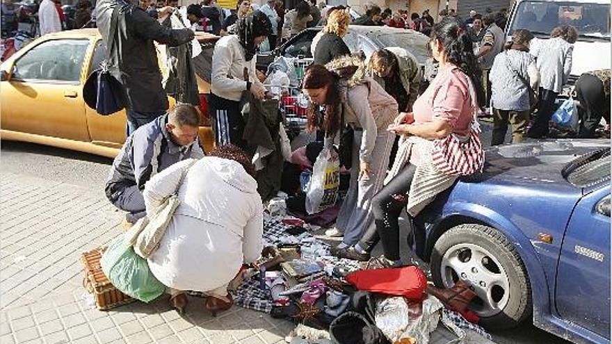 en busca de gangas. Varias personas curiosean entre las prendas y la quincalla que ofrece una de las vendedoras, atenta a la llegada de la policía local.