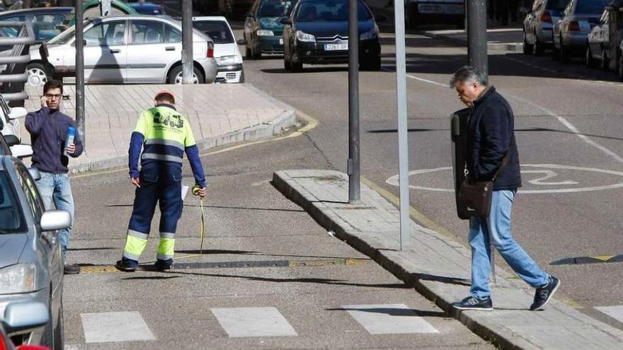 Un trabajador mide el ancho de la calzada al otro lado de la calle.