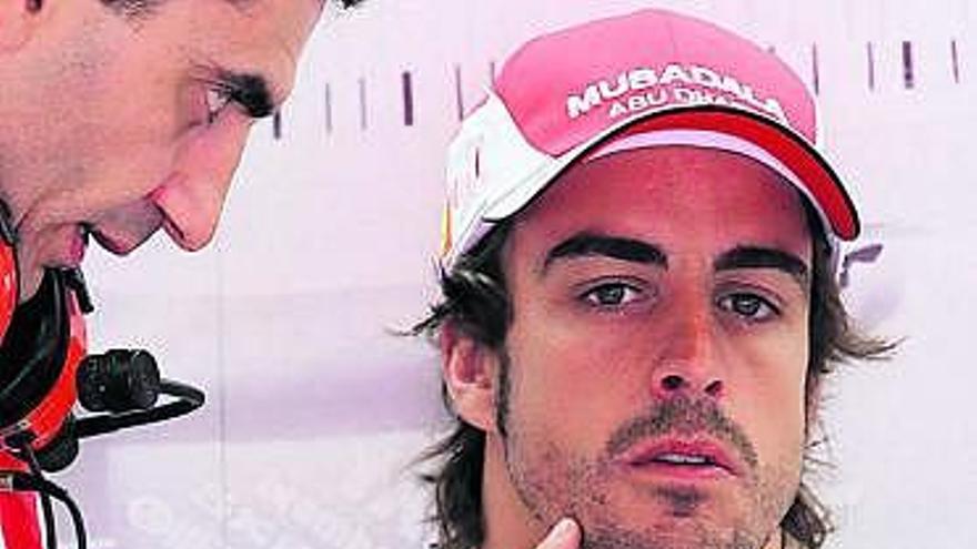 Alonso atiende en el box de Ferrari las indicaciones de uno de sus ingenieros.