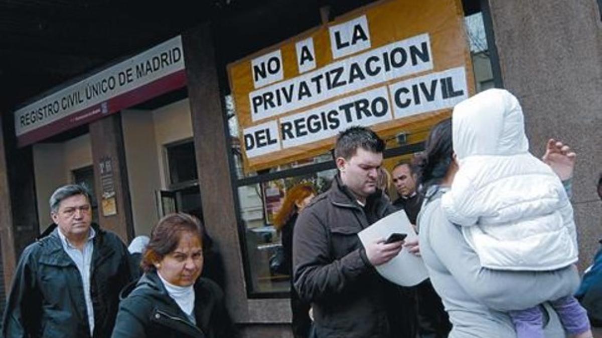 El exterior de un registro civil en Madrid, el pasado lunes, con un cartel que muestra las críticas a la privatización de este servicio público.
