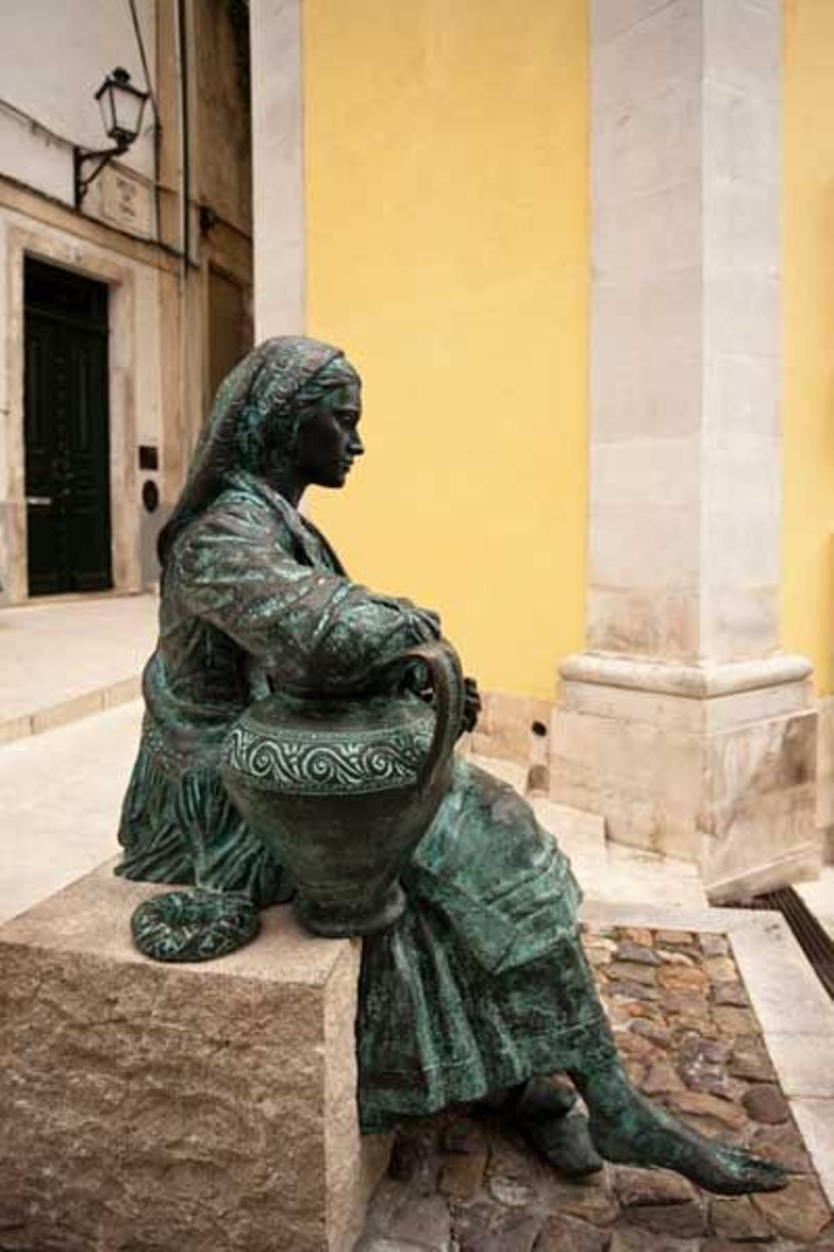 Estatua de una mujer sentada en las calles de Coimbra.