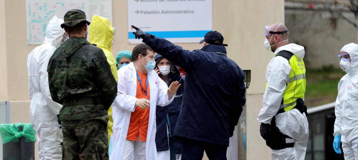 Sanitarios conversan con personal militar mientras trabajan en un hospital de campaña montado cerca del acceso de Urgencias del Hospital Gregorio Marañón.
