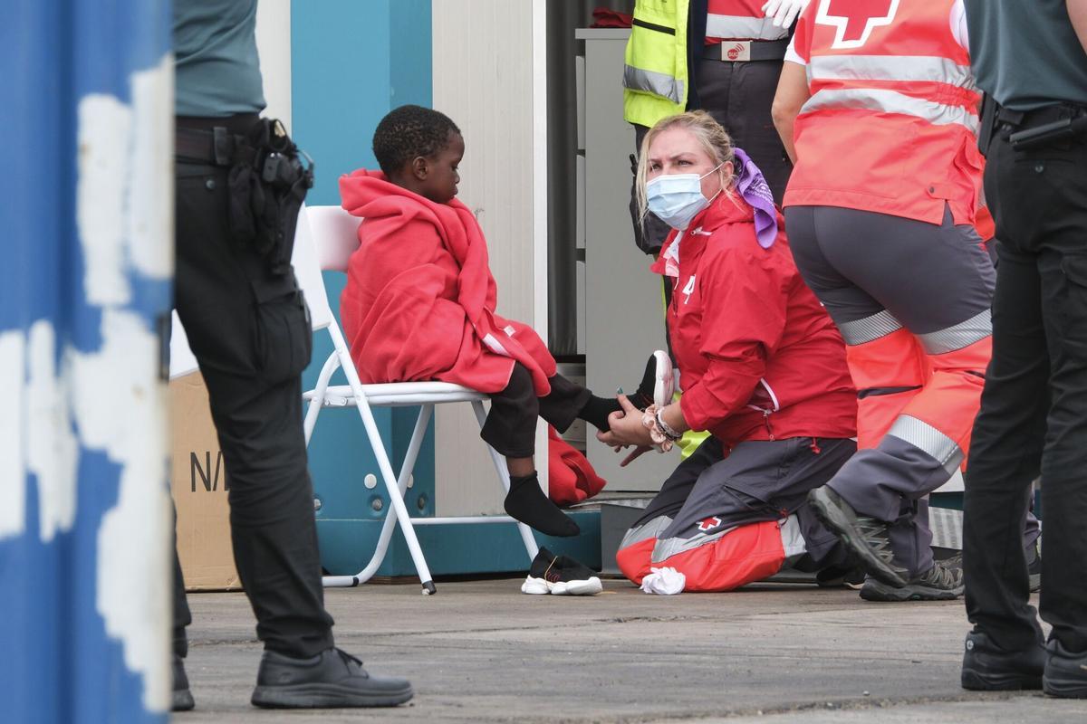 Foto de archivo de una voluntaria de Cruz Roja atendiendo a un menor migrante no acompañado.