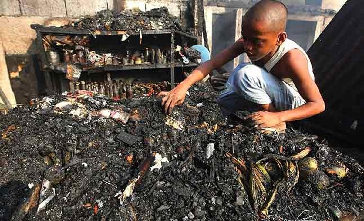 Un nen filipí torna a casa seva arrasada pel foc, a recollir el material reutilitzable. Un incendi va destruir la casa a Ciudad Quezon, a l’est de Manila (Filipines).