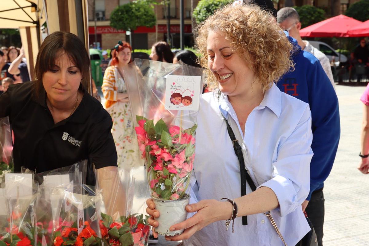 Una vecina recoge una de las 1.500 plantas que han regalado por el Día de la Madre.