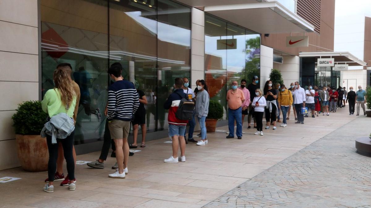 Una larga cola de clientes espera para entrar en una tienda del Viladecans The Style Outlets este lunes