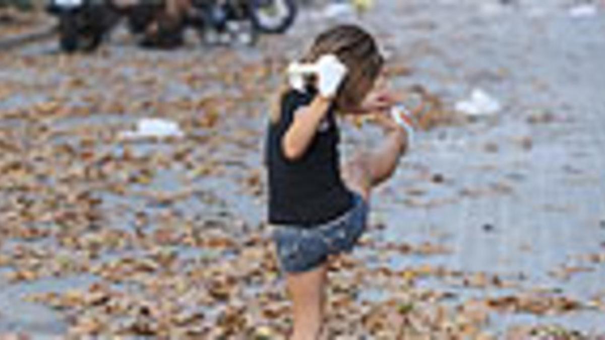 Una niña juega con las hojas caídas de los plátanos en Barcelona.