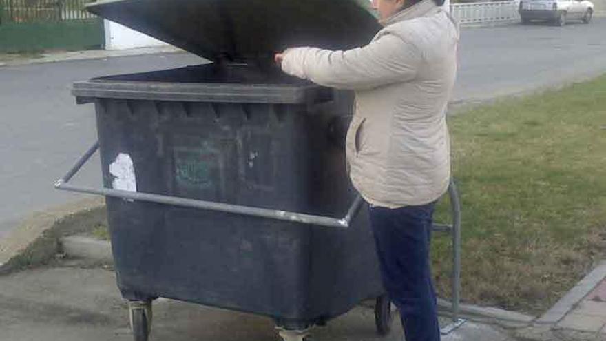 Una vecina de Santa Colomba arroja basura en un contenedor sujeto por anclajes.