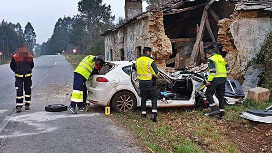 Efectivos de la Guardia Civil y de emergencias junto al coche que sufrió el accidente en Aranga,