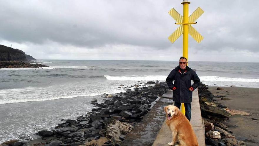 José Manuel Peláez y su perro, junto a la señal luminosa instalada en la bocana de la ría de Navia.