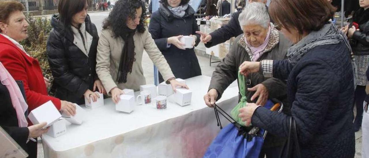 Las representantes del CIM repartieron tazas con una viñeta de Luis Davila en el mercadillo. // S.A.