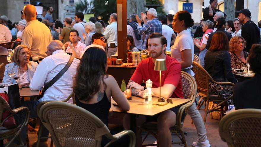 Varias personas en una terraza durante una manifestación contra la masificación turística.