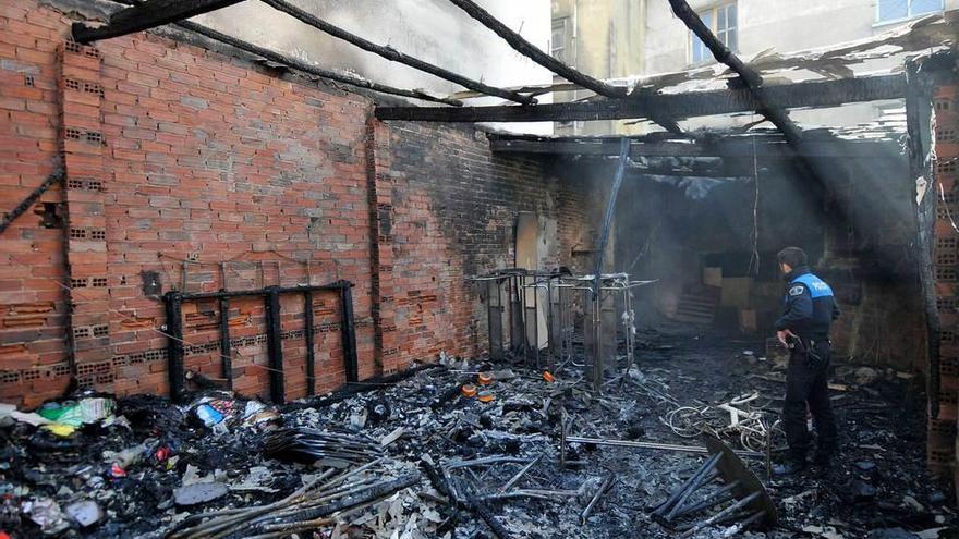 Un agente de la Policía Local controla los restos del incendio del almacén horas después de la quema.