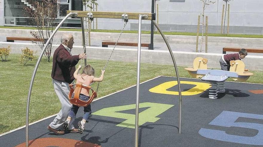 Un abuelo juega con sus nietos en un parque infantil de A Coruña. // Juan Varela