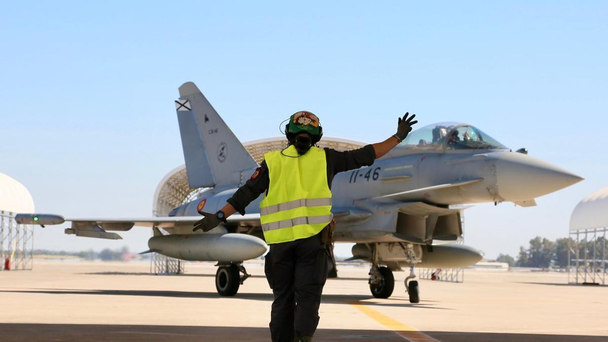 Una asistente en tierra guia a un caza del Ejército del Aire.