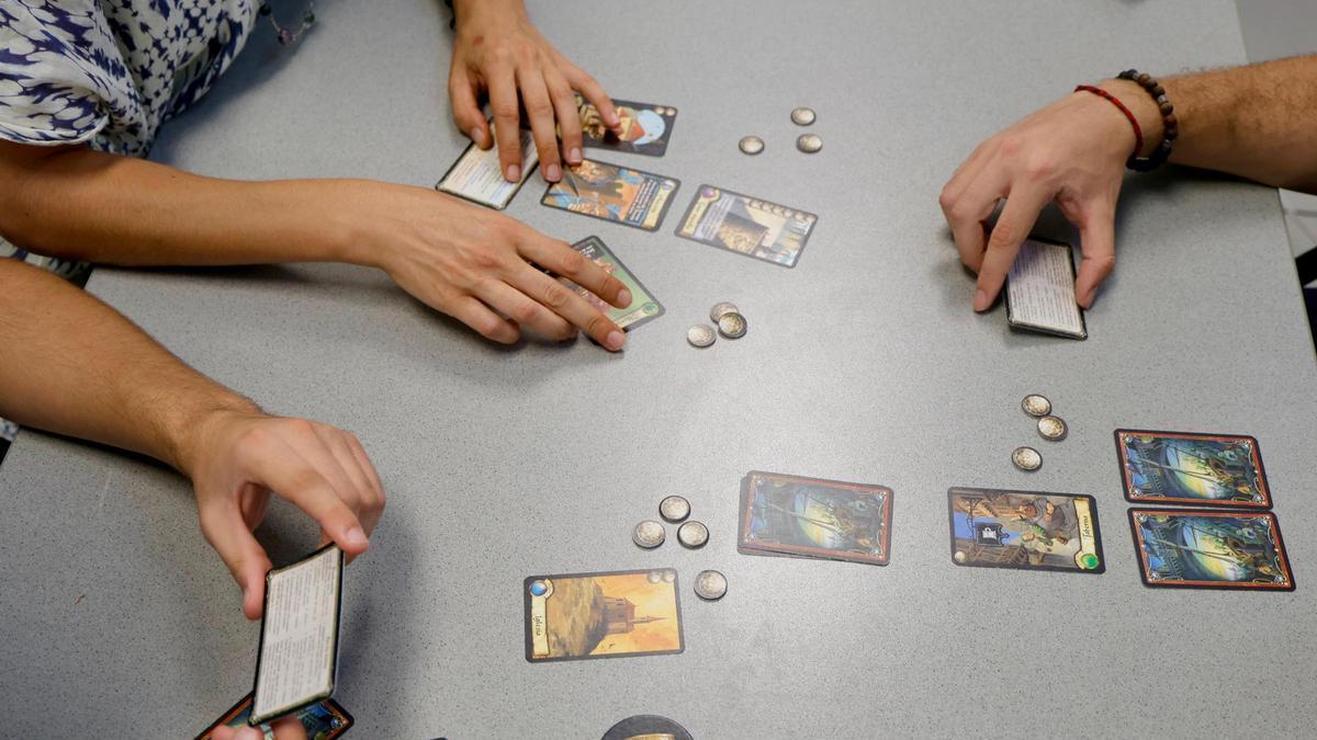 Varias personas jugando al juego de mesa clásico como 'Ciudadelas'.