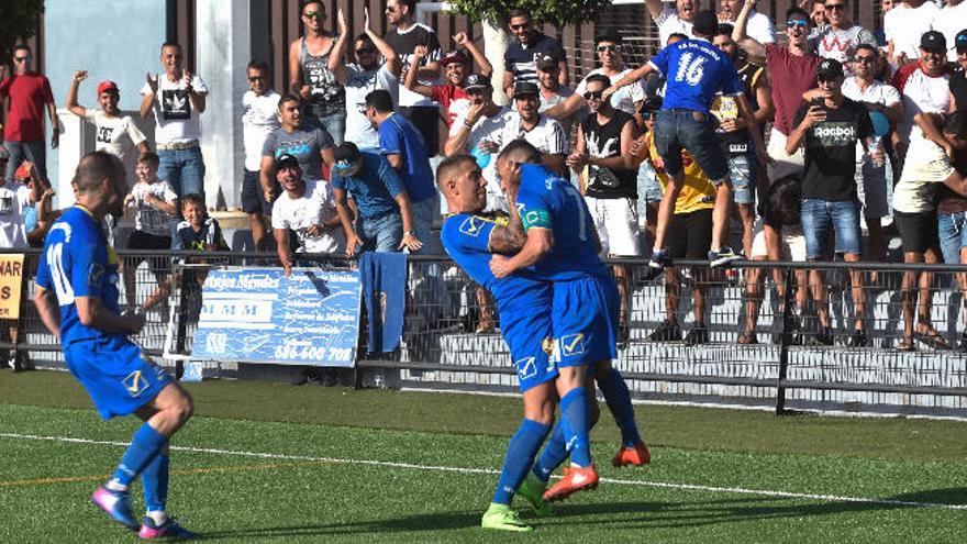 Jefté levanta a Karim, autor del primer tanto de la UD San Fernando ante el Écija Balompié en presencia de Cesáreo, quien al filo del descanso haría el 2-0.