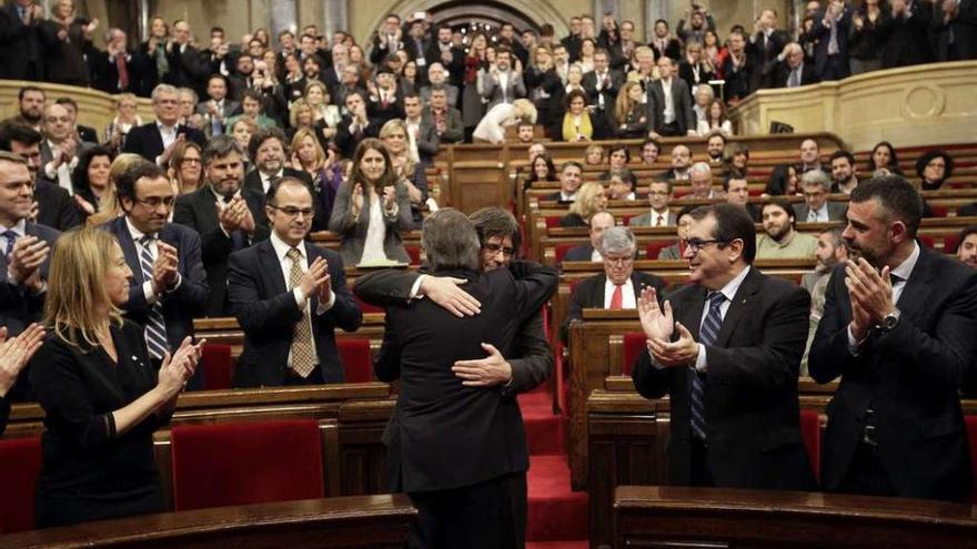 Mas (de espaldas) y Puigdemont se abrazan antes de empezar el pleno de investidura del nuevo presidente de la Generalitat. // Efe