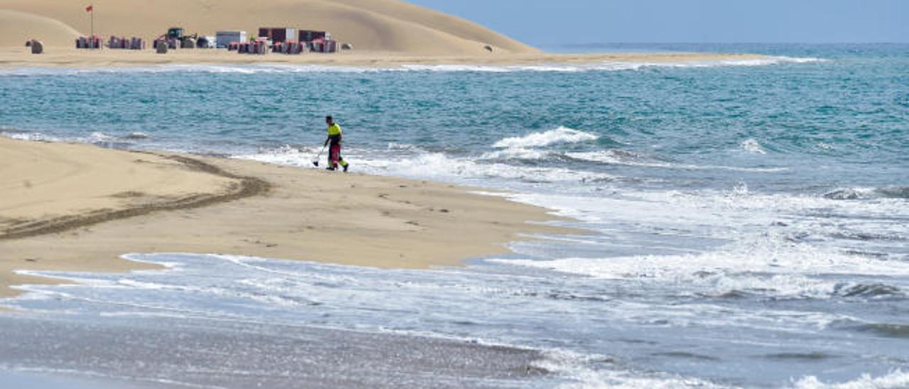 Un operario limpia la playa de Maspalomas, en el sur de Gran Canaria, vacía por el cierre turístico.