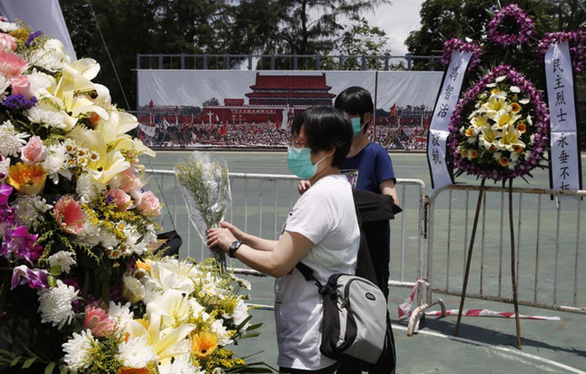 Dues dones col·loquen flors al memorial a les víctimes de Tiananmen, a Hong Kong.