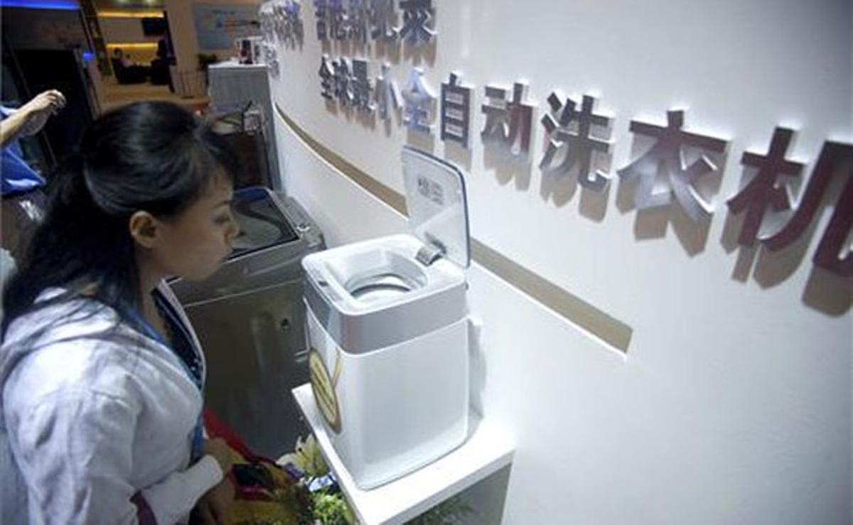 Una noia contempla la rentadora més petita del món durant la fira d’electrònica de consum Sinoces 2011, a Qingdao (Xina).