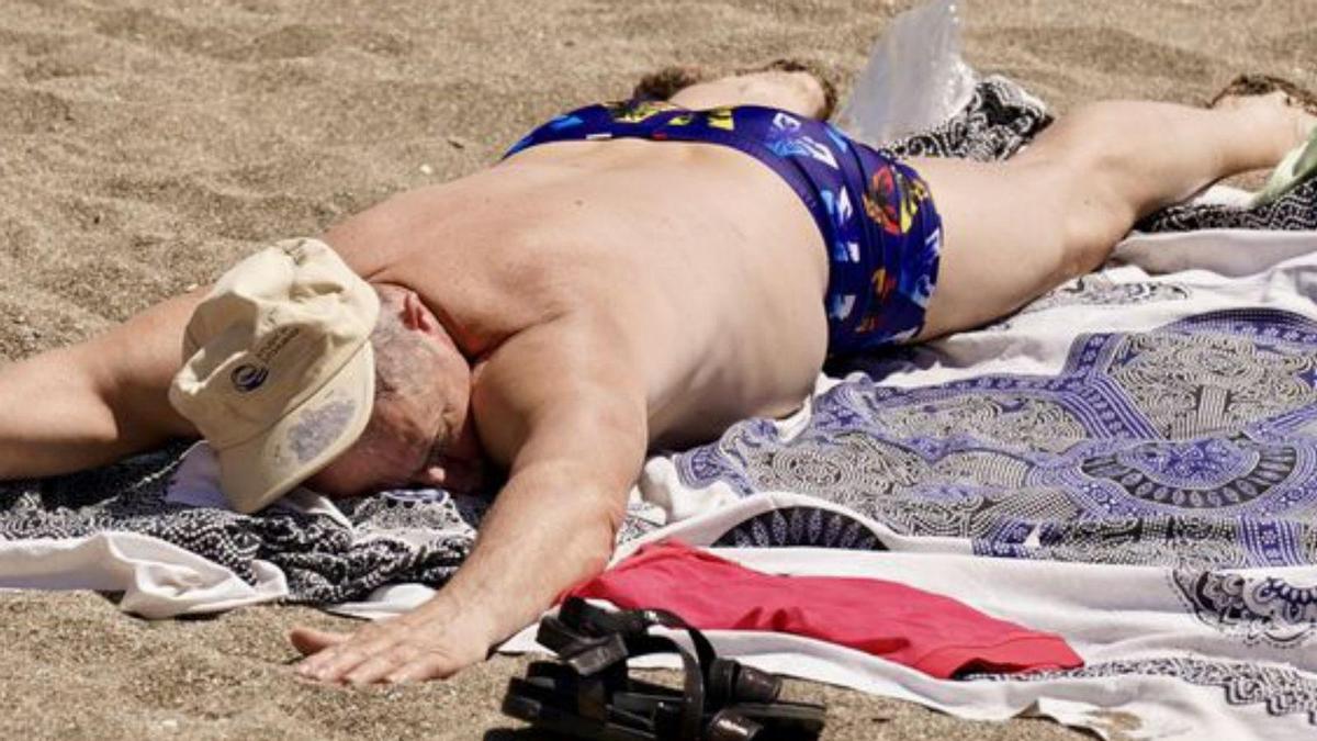 Un hombre tumbado en la arena de la playa.