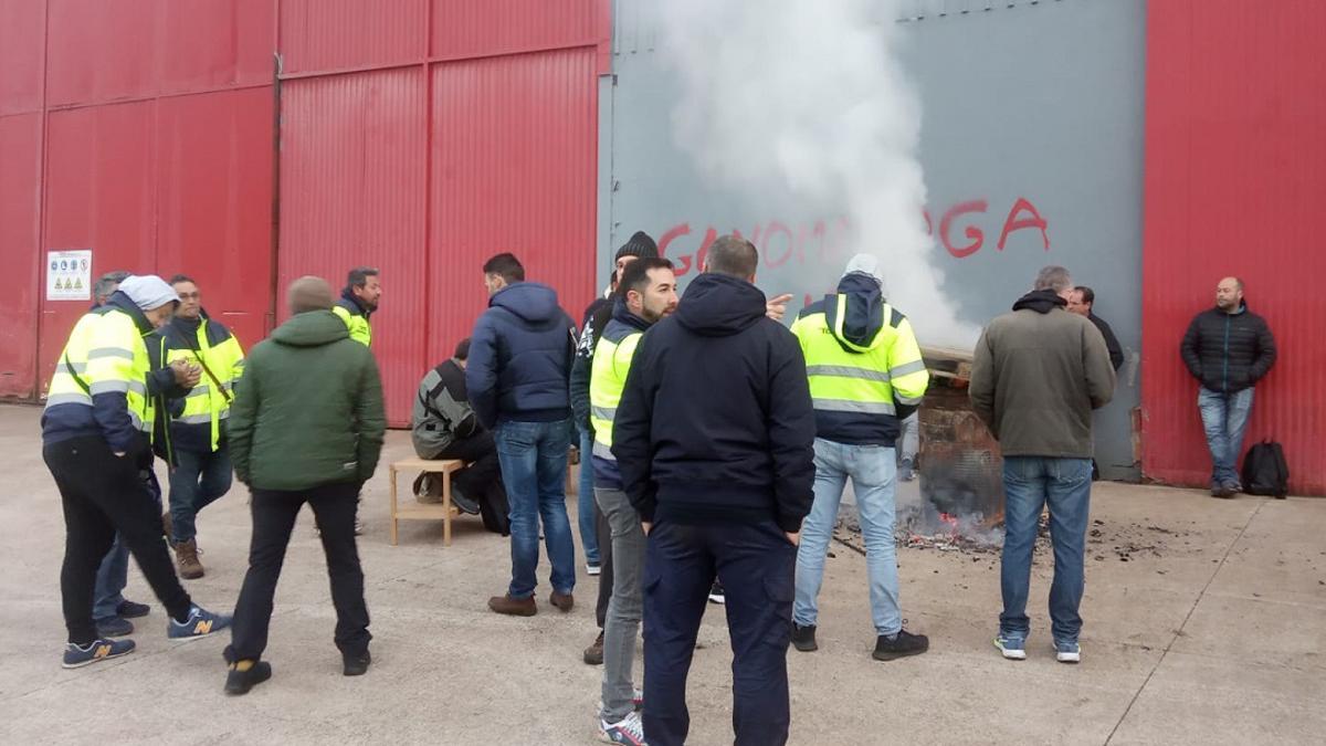 Entrada de la fábrica, con los trabajadores calentándose con una estufa improvisada