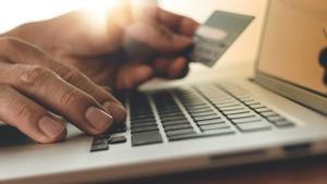 Archivo - Persona usando un ordenador con tarjeta de crédito y haciendo compras online