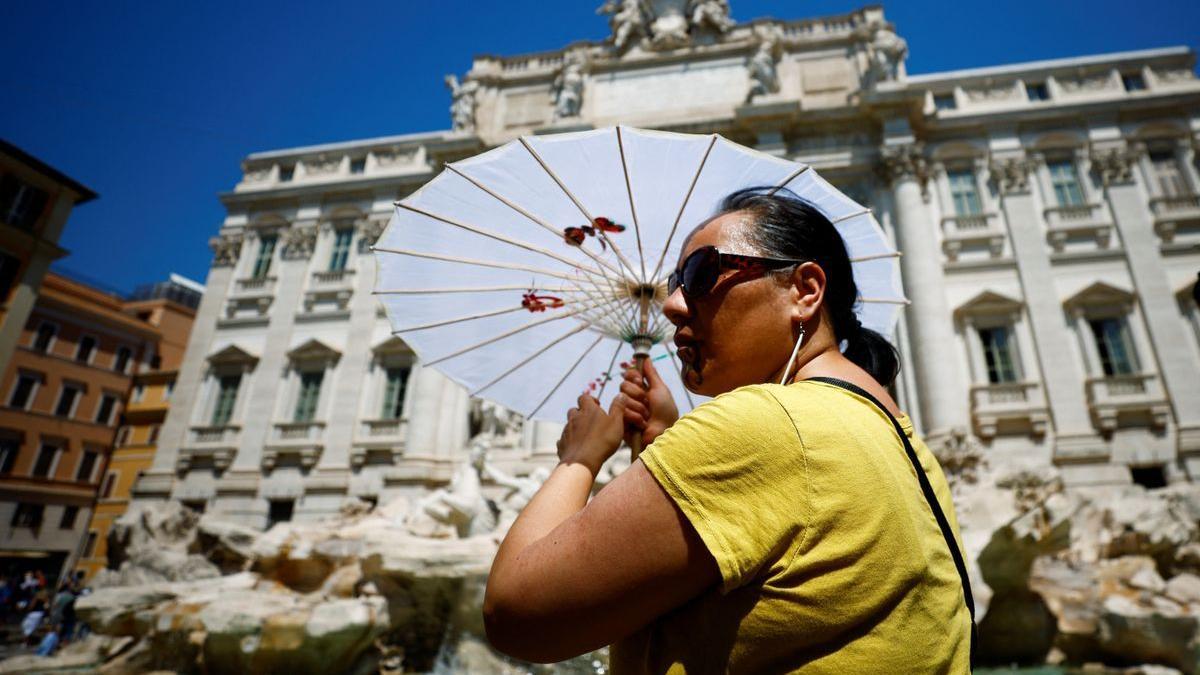 Una turista se refugia del calor en la Fontana di Trevi.