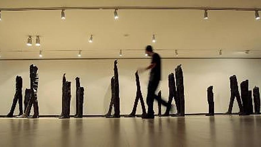 Un hombre pasa junto a la instalación &quot;Standing figures&quot;, de la escultora polaca Magdalena Abakanowicz, que presenta en el Instituto Valenciano de Arte Moderno (IVAM) su nueva exposición de doce instalaciones realizadas entre 1973 y 2000, que revelan su dominio con materiales tan diversos como el bronce, la madera, el hierro o el nylon.