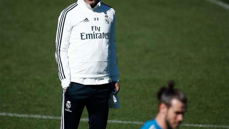 Zinedine Zidane sigue las evoluciones de Gareth Bale, ayer en Valdebebas. // Europa Press
