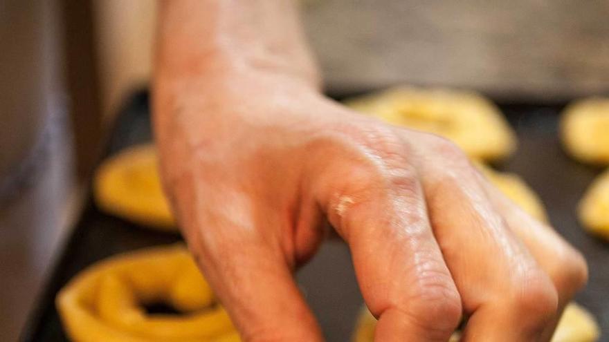 Detalle de la mano de una elaboradora de marañuela de Candás dando forma a uno de estos dulces.