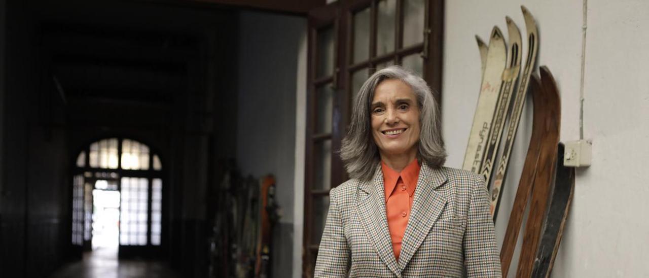 Guillermina Caicoya posa junto a algunos de los esquís de la familia -los de su padre, Elías Caicoya Masaveu, de madera oscuros, y con los que ella compitió en la selección nacional, los blancos- en el edificio de la calle Principado en cuya portería tiene ahora la sede de su galería.