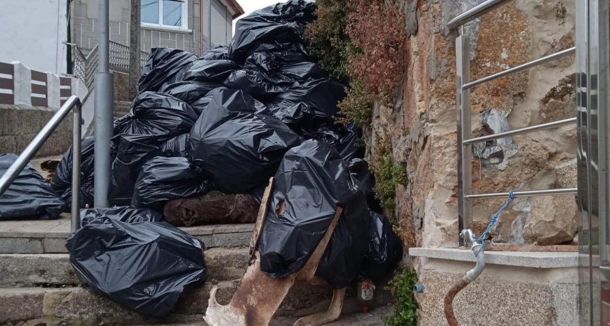 Las bolsas que el Concello sacó de la vivienda de la vecina fallecida, en la limpieza. | FDV