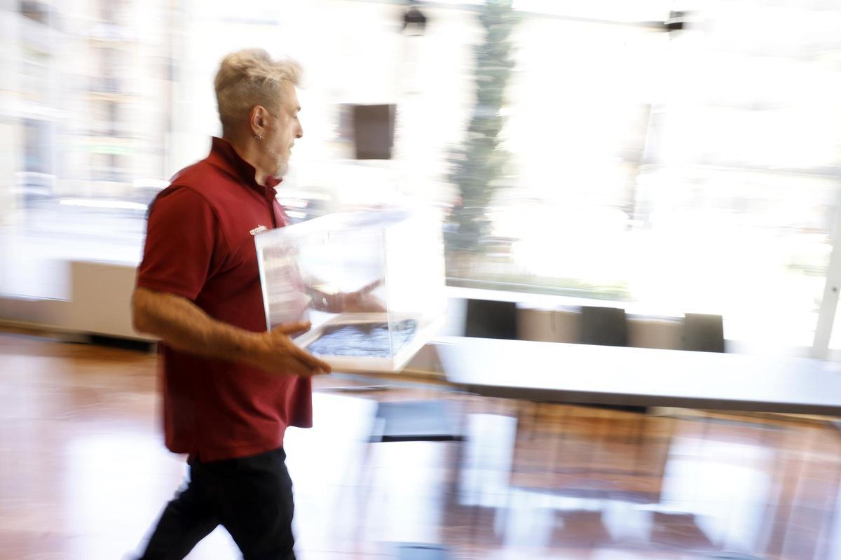 Un operario transporta una hurna en un colegio electoral.