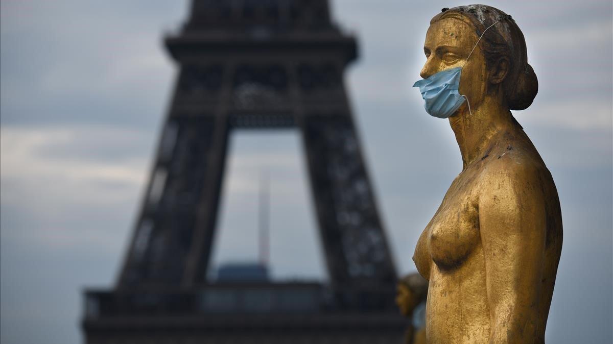 Máscaras en las estatuas de la explanada de Trocadero, durante el cierre contra el brote de coronavirus. La torre Eiffel es visible al fondo.